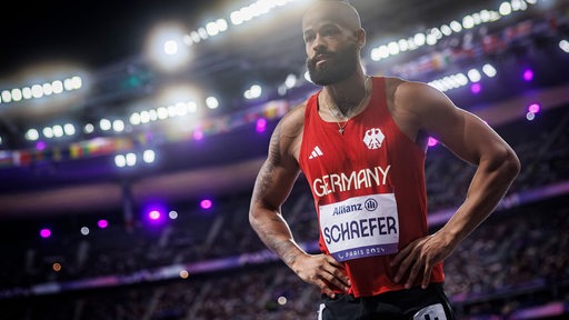 Para-Sprinter Leon Schäfer steht konzentriert mit den Händen in die Hüfte gestützt beim Start.