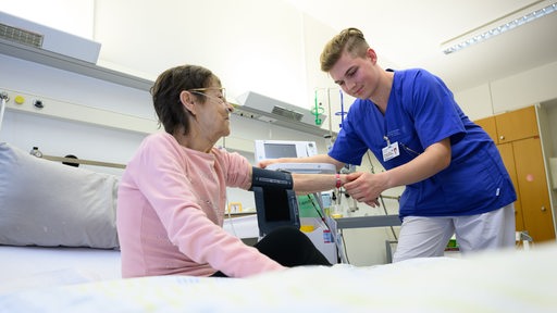 Eine Pflegekraft misst den Puls bei einer Patientin in einer Klinik