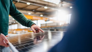 Ein Mann hält ein Teil einer Solaranlage in den Händen