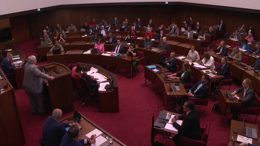 In dem Plenarsaal in der Bremischen Bürgerschaft sitzen viele Menschen an den Plätzen.