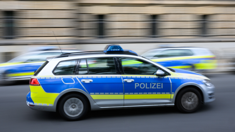 Ein Polizeiauto fährt zu einem Einsatz, Hintergrund verschwommen, andere Polizeiwagen fahren in andere Richtung