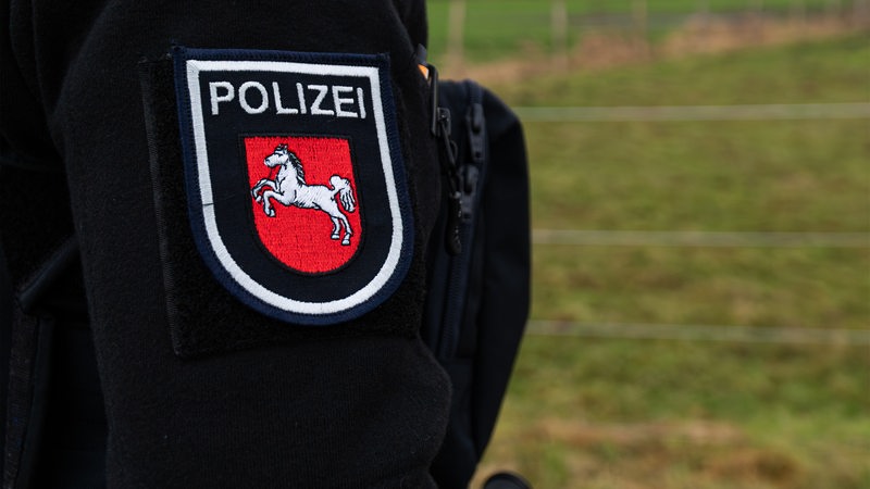 Ein Beamter der Polizei mit dem Wappen von Niedersachsen auf der Uniform.