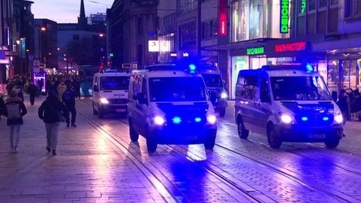 Zwei Polizeiautos führen einen Demozug an.