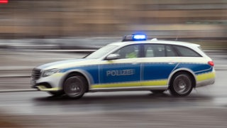 Ein Polizei fährt mit Blaulicht auf einer Straße.