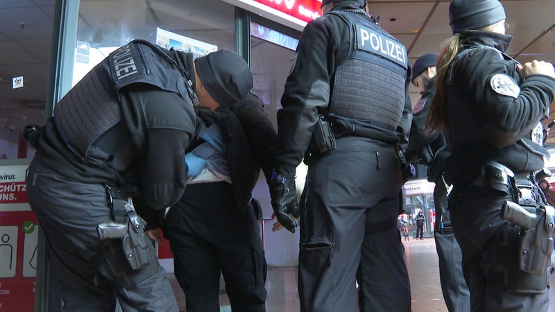 Polizisten kontrollieren im Bahnhof einen Mann