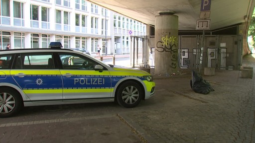 Ein Polizeiwagen steht unter einer Brücke. 