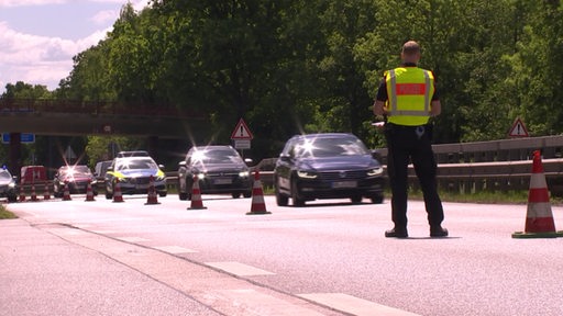 Ein Polizist mit Warnweste steht auf der Straße.