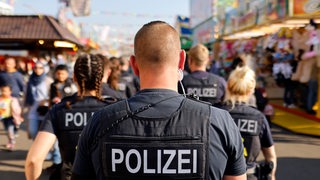 Polizisten gehen über ein Volksfest.