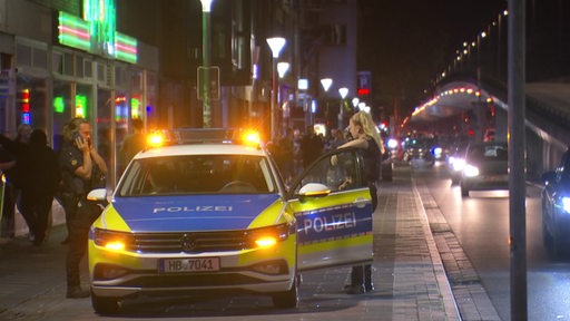 Zwei Polizisten stehen an einem Politzeiwagen in der Bremer Hochstraße Breitenweg