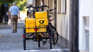 Ein Fahrrad von der Deutschen Post steht an einer Straße.