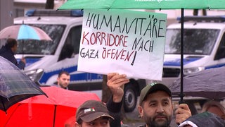 Ein Mann hält auf einer Demo ein Schild hoch.