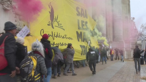 Mehrere Protestierende hissen ein Banner der französischen Confédération paysanne union