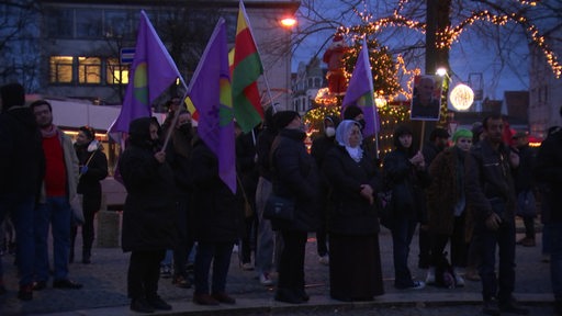 Protestierende mit Fahnen in der Dämmerung.