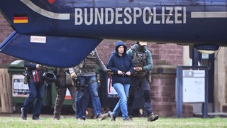 Im Innenhof eines Behördenzentrums wird die frühere RAF-Terroristin Daniela Klette zu einem Hubschrauber geführt. Zuvor hatte sie einen Haftprüfungstermin beim Bundesgerichtshof (BGH).