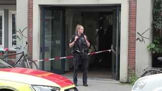 Eine Polizisten steht vor einem Absperrband.