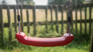 Eine leere Kinderschaukel in einem Park.