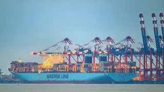 Ein Containerschiff lieft in einem Hafen.