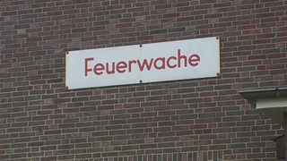 An einer Wand hängt ein Schild der Feuerwache.