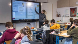 Lehrerin steht vor einer Schulklasse und unterrichtet 