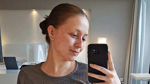 Eine junge Frau macht ein Selfie in ihrem Zimmer