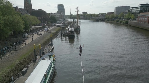 Ein Mensch auf der Slackline, die über der Weser gespannt ist