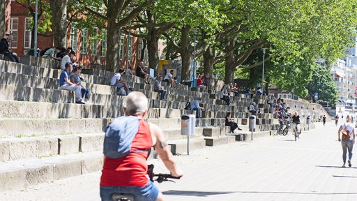 Menschen sitzen auf den Stufen an der  Schlachte, im Vordergrund eine Fahrradfahrerin