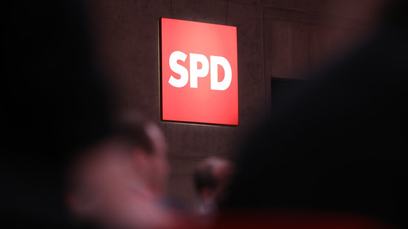 Leuchtenes SPD Logo, davor unscharf Menschen (Symbolbild)