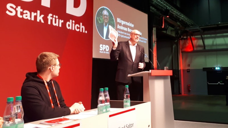 Bürgermeister Bovenschulte hält das Wahlprogramm in die Höhe.