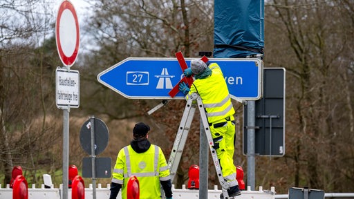 Ein rotes Kreuz wird über dem Autobahnschild der A27 angebracht. (Archivbild)