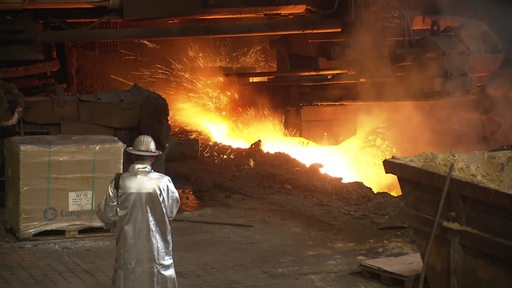 Ein Mitarbeiter steht vor einem Feuer im Stahlwerk.