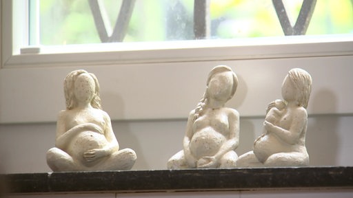 Drei kleine Statuen von schwangeren Frauen auf einer Fensterbank