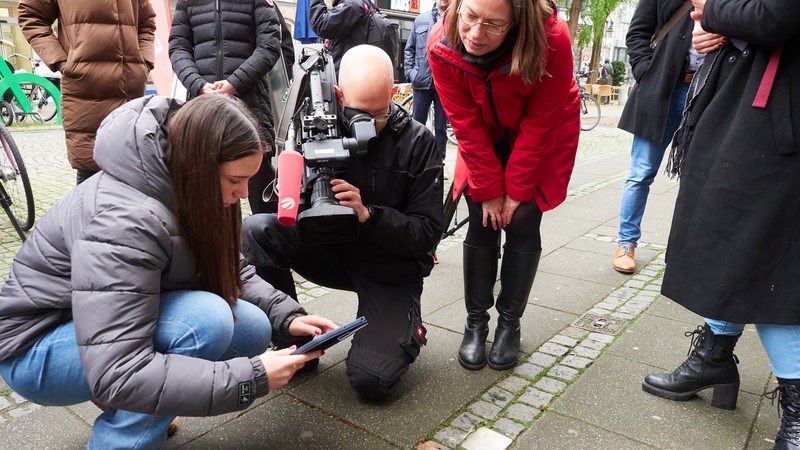 Schülerin Ida von der Wilhelm-Focke-Oberschule zeigt mit Senatorin Aulepp, wie die Stolperstein-App Erinnerung lebendig macht. 