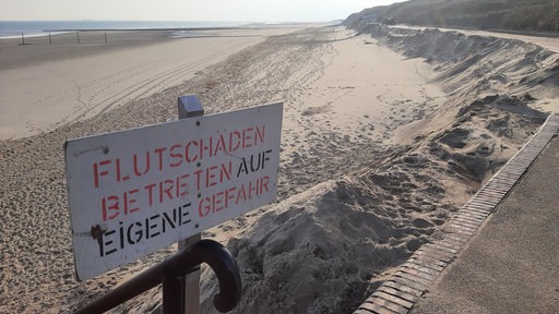 Ein Schild mit der Aufschrift "Flutschäden Betreten auf eigene Gefahr" weist am Strand der ostfriesischen Insel Wangerooge auf fehlenden Sand am Strand hin.