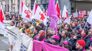 Rund 250 studentische Mitarbeiter halten bei einer Demonstration Banner und Fahnen in die Höhe.