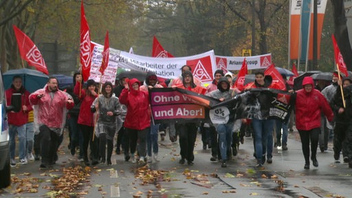 Angestellte der IG Metall streiken mit Bannern auf einer Straße.