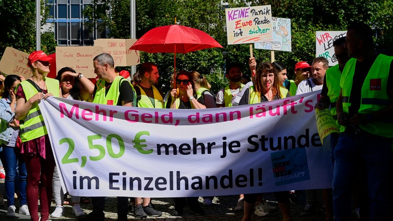 Menschen mit einem Banner mit der Aufschrift: "Mehr Geld im Einzenhandel"