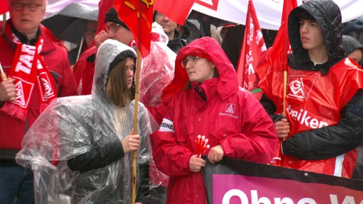 Streikende Personen in roter Regenkleidung.