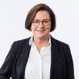 Das Portrait einer Frau mit mittellangem Haar und einer Brille.