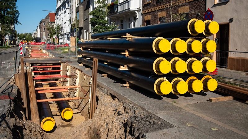 Ein Stapel neuer Rohre für Fernwärme liegt an einer Baustelle.