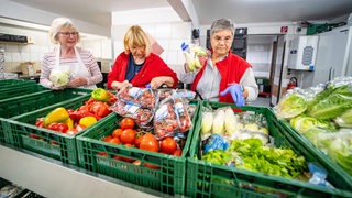 Drei Frauen sprtieren Lebensmittel bei der Tafel.