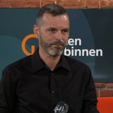 Ein Mann mit Bart steht in einem Fernsehstudio