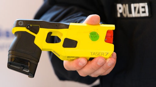 Ein Polizeibeamter hält einen Taser 7 in der Hand