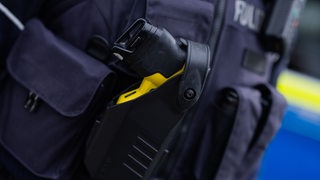 Ein Taser steckt im Holster einer Polizistin.