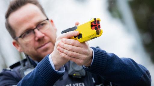 in Polizeibeamter demonstriert einen Taser im Trainingsmodus ohne scharfe Munition. 