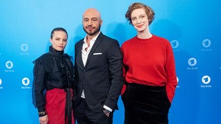 Jasna Fritzi Bauer, Dar Salim und Luise Wolfram stehen für die Presse vor einer blauen Wand