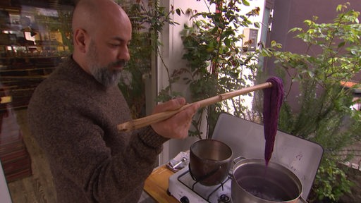 Daniel Rofoogar-Matin, Teppichrestaurator, färbt die Teppichfäden in purpurrot.