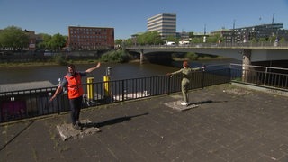 Zwei Personen stehen auf Fundameten an der Weser.