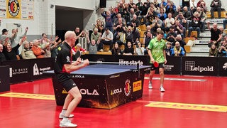 Werders Tischtennis-Profi Kirill Gerassimenko schaut enttäuscht nach dem verlorenen Spiel zu Boden, während sein Gegner Daniel Habesohn jubelt und von den Zuschauern gefeiert wird.