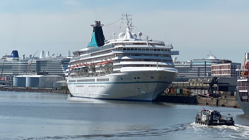 Ein Kreuzfahrtschiff liegt im Hafen, im Hintergrund liegen weitere Kreuzfahrtschiffe.