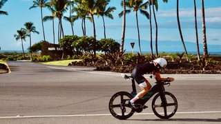 Der Bremer Triathlet Rainer Koschke auf der Radstrecke vor Palmen bei der Ironman-WM auf Hawaii.